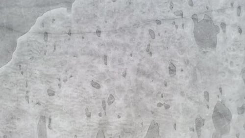 AERIAL: Vertical Drone Shot of Flying Very Low and Close to the Frozen Lake Surface on a Cloudy Day