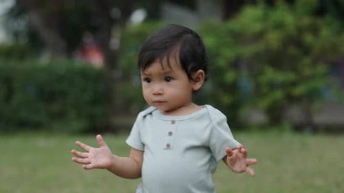infant baby learning to walking first step on a green grass in park