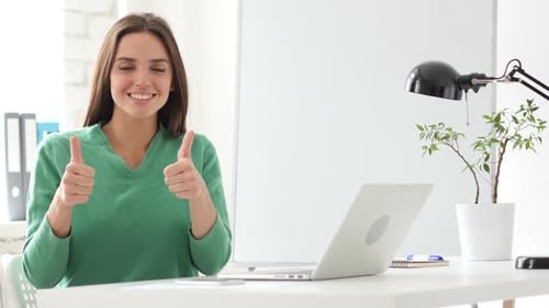 Woman at Desk Gives Thumbs Up in Office