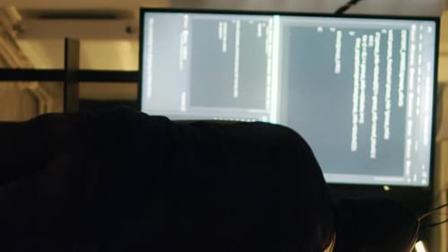 Hooded Programmer Working at Night in Dark Room