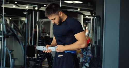 Closeup on Bodybuilder Male Hands Putting Protection Gym Belt for Weight Training Cropped View on