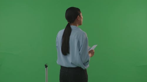 Asian Woman Traveler With Luggage Looking At The Passport And Looking Around In The Green Screen