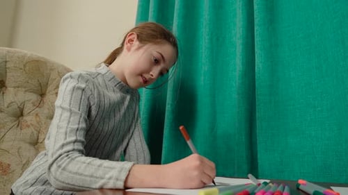 Young Girl Drawing with Markers at Table