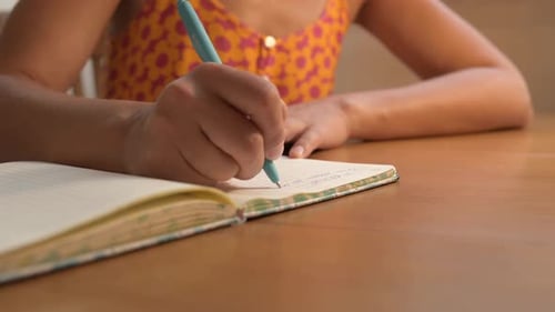 Woman Writing in Notebook on Desk Indoors