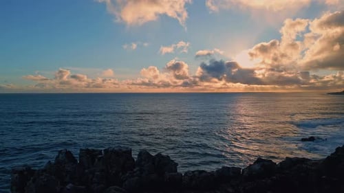 Amazing evening seascape drone view on rocky shore under bright sunset light