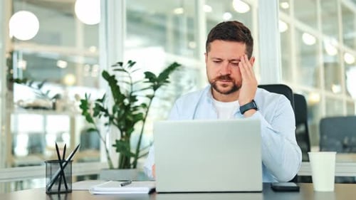 Stressed Businessman Suffers From Headache While Working in Office