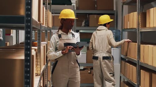 Female Employee in Overalls Checking Tablet Inventory