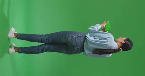 Back View Of Woman Using Mobile Phone With Mock Up Green Screen On Green Screen In The Studio