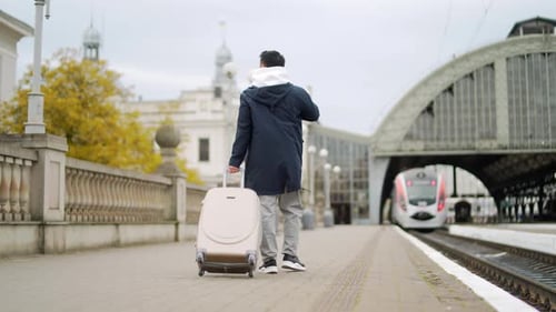 Traveler Rolling Luggage at a Train Station