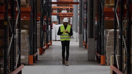 Supervisor recorriendo el almacén comprobando el inventario en cámara lenta