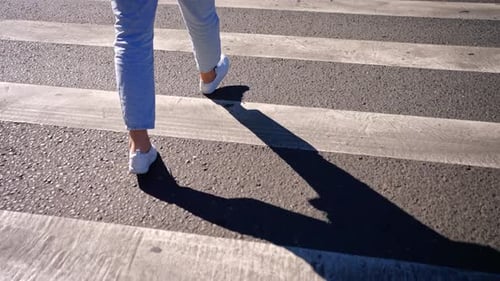 Mulher andando na travessia de pedestres em dia ensolarado