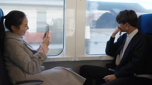 Couple Rides Train Through City, Using Phone