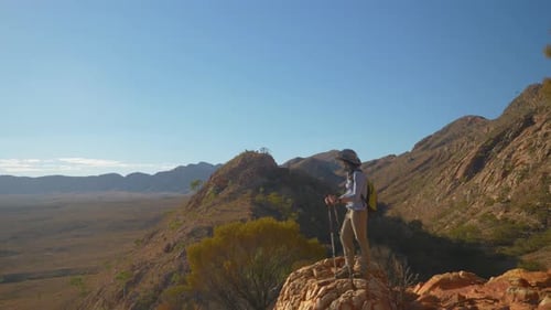 Pan past hiker admiring view from rugged mountain, Central Australia