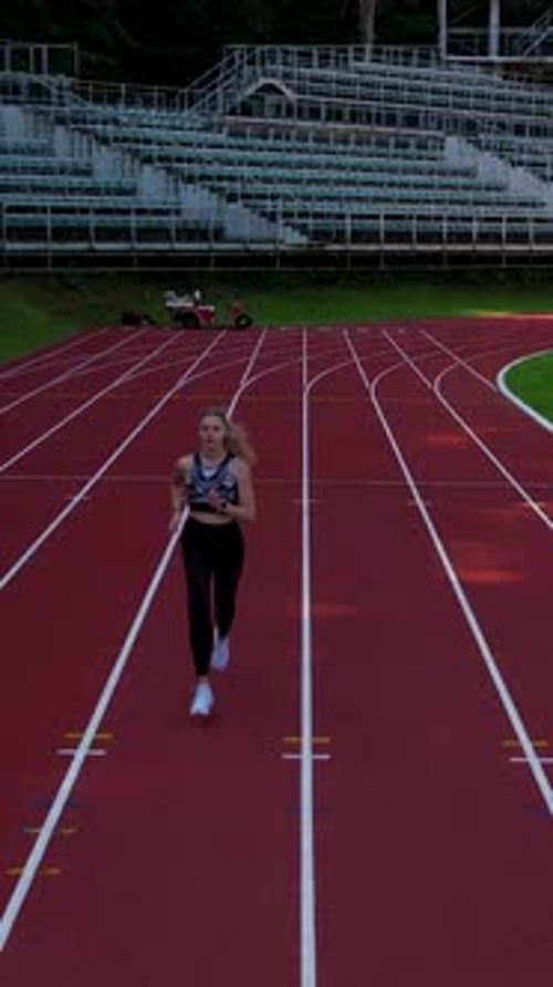 Young Woman Running On Outdoor Track At Sports Stadium