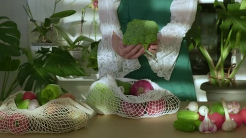 Mujer desempacando frutas y verduras de una bolsa ecológica en una cocina blanca