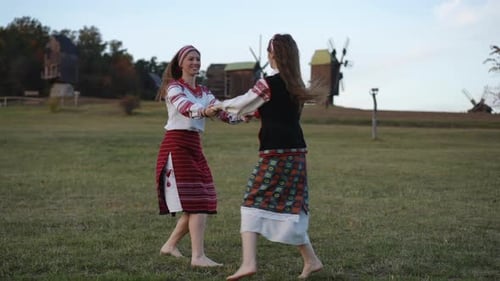 Women Dancing in Traditional Clothing on Grassy Field