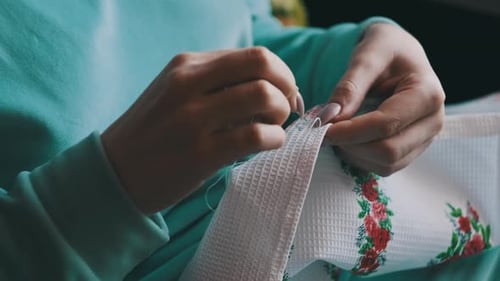 Woman Sews Floral Design on White Fabric Close Up