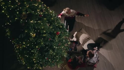 Top View of a Young Woman and a Little Girl Decorating a Christmas Tree with Ornaments and Lights