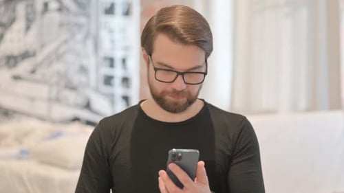 Man with Phone Celebrates Success Indoors