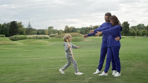 A Boy Runs Up and Hugs His Parents on a Walk in the Park