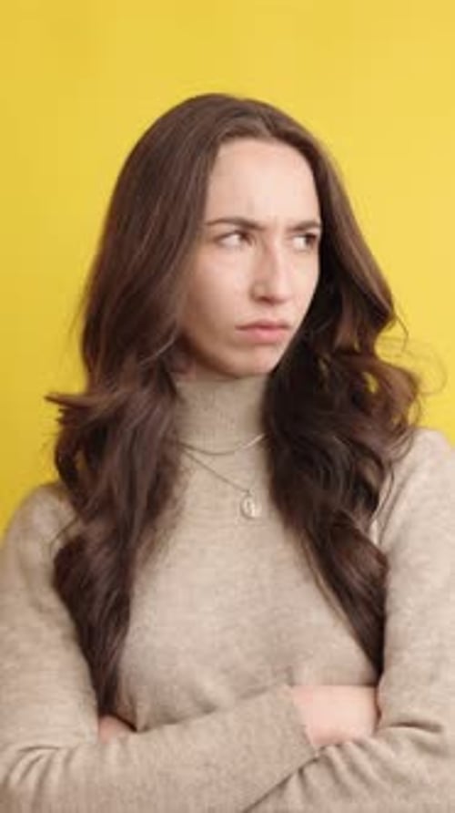 Woman Looks Annoyed with Arms Crossed on Yellow