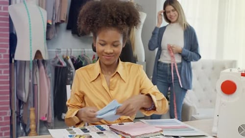 A young African American designer in a yellow dress is thinking about a shirt design with passion