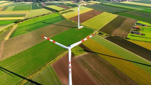 Windmill blades rotate in the field. Aerial view on the wind turbine