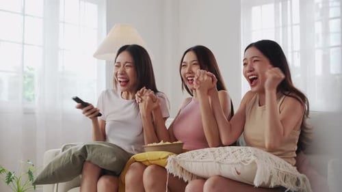 Three Friends Cheering While Watching Television Together