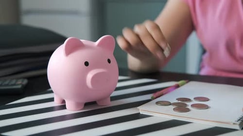 Nahaufnahme einer Frau, die Münzen im Sparschwein rettet