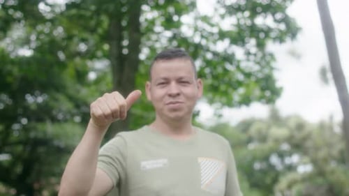 Smiling Man Gives Thumbs Up in a Green Park