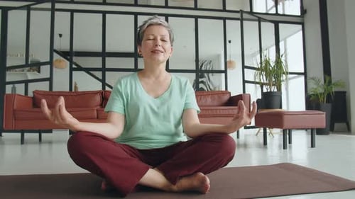 Woman Meditating Cross-Legged on Yoga Mat Indoors