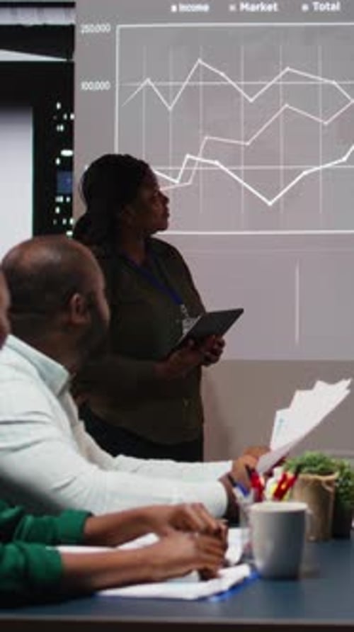 Vertical Video Multiethnic Experts Team Evaluating Data Performance Metrics on Projection Board
