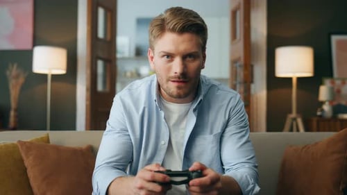 Man Plays Video Game with Controller On Sofa