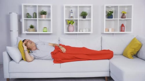 Man Lying on Sofa Under Blanket