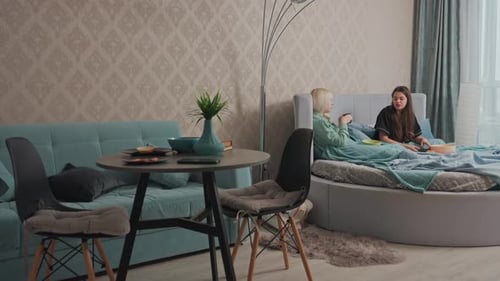 Two Young Women Relaxing and Eating in Apartment