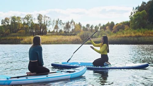 Women Paddle Boarding Together on a Quiet Lake