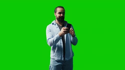 Young Carefree Man Checking His Mobile Phone Against Green Screen Backdrop