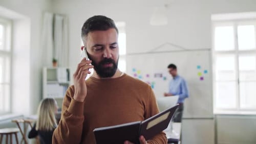 Mature hipster businessman works with smartphone in modern open plan office space