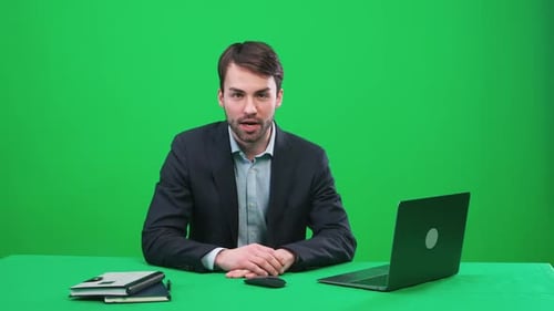 Man Reporter Sits in the Studio and Looks Into the Camera Speaks and Hosts a News Programon a Green