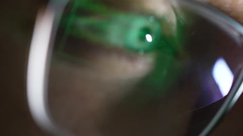 Blurred Vision of a Computer Screen with Code Reflecting on the Surface of Eyeglasses