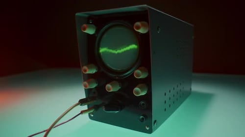 Osciloscópio com cabos conectados exibindo forma de onda verde