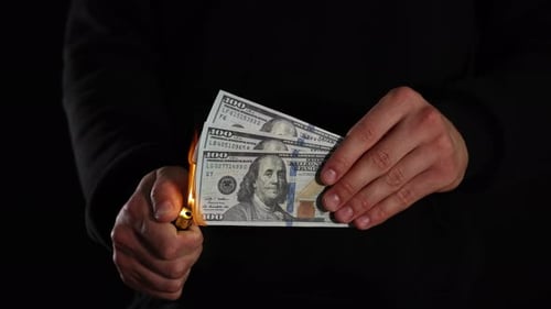 Man burning dollar banknotes on black background, closeup
