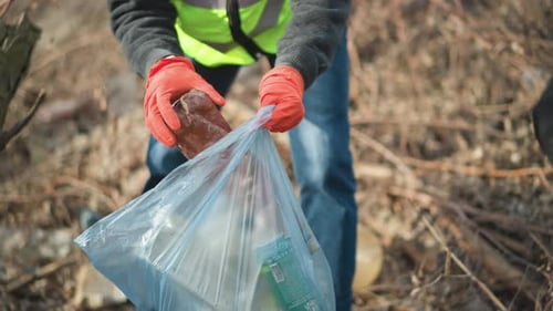 Adult Picking Up Trash in Nature Environment