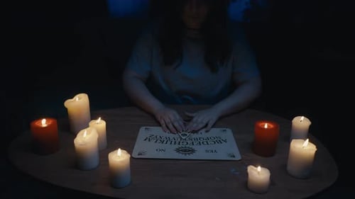 Video Capturing a Woman's Figure Having an Ouija Board Session Seance Surrounded By Candles in the