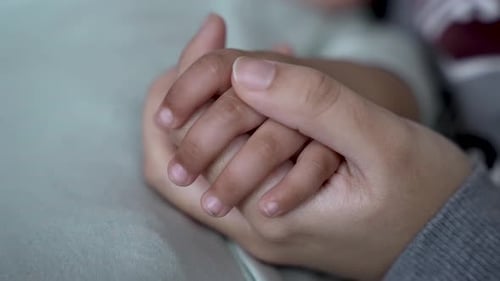 Adult Holding Infant's Hand in Loving Gesture