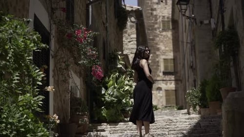 A Young European Woman Looks at the Camera Before Climbing Some Stone Stairs on a Rural Street