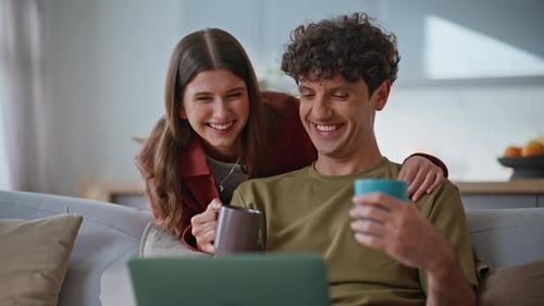 Couple Relaxing on Couch with Laptop and Coffee
