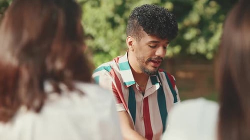 Close-up of young man sitting in park having picnic, talking with friends