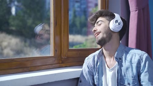 Man Listening to Music by the Window