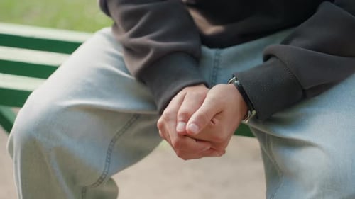 Nervous Hand Movements Quiet Moment on Park Bench Individual Displaying Anxious Gestures Outdoors